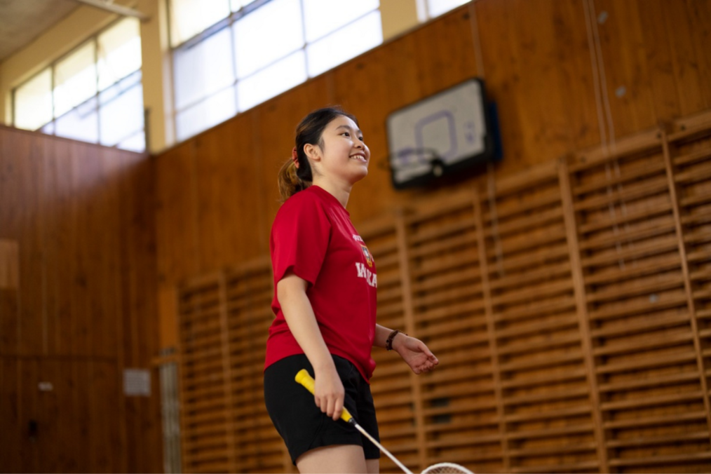 Girl in gymnasium holding badminton racket